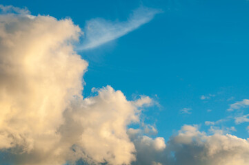 Obraz premium Sunset sky landscape with golden fluffy clouds in the blue sky, evening sky view