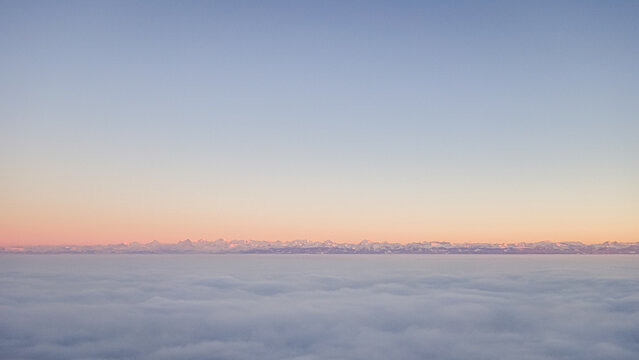 Snowy peaks of Jura at sunrise with cloud blanket