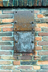 two square rusty metal plates attached to a stone wall