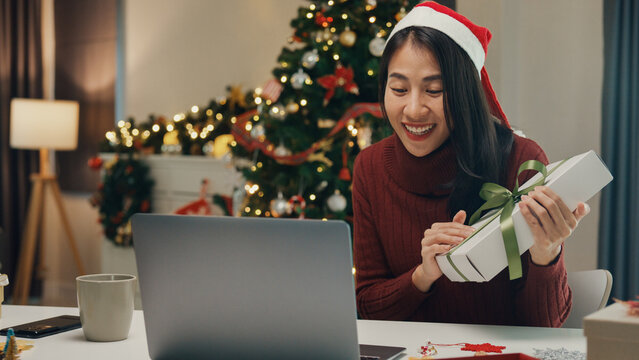 Attractive Asia female blogger new normal shopping online christmas gift unbox review celebrate christmas video conference call with follower on computer laptop in social media platform at house.