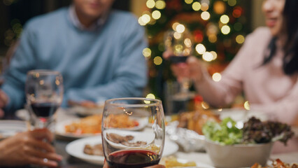 Group of Asia colleague gathering New year holidays party together. Close-up Happy friends group drink glasses of wine start eat christmas dinner at home in evening, celebration and people concept.