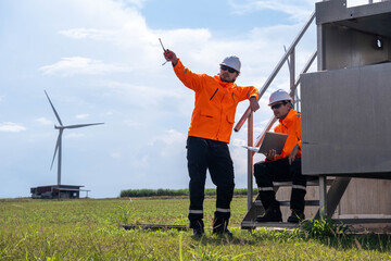 Engineers conducting site assessment at a wind farm in bright orange jackets under a cloudy sky © Freeday photo