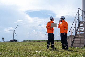 Technicians review project plans and discuss wind turbine installation at a renewable energy site...