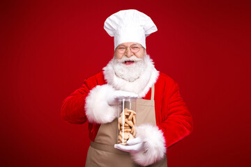 Santa the chef in his red costume offers a jar of cookies smiling in a festive kitchen style portrait perfect for holiday campaigns