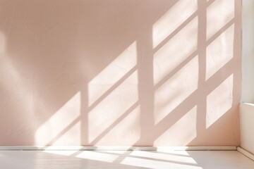 Obraz premium Soft morning light filters through a window, casting geometric shadows on a beige wall. The gentle interaction of light and shadow creates a peaceful and warm atmosphere
