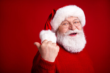 Santa Claus in a cozy red sweater gives a thumbs up against a bright christmas red backdrop ready for holiday fun and festive shopping