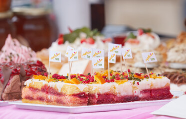 Punch slices at Naplavka, vibrant layers of pink and yellow sponge, subtly soaked in punch syrup, topped with a smooth, glossy glaze, with pieces of orange and crushed pistachios, delicacy.