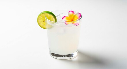A refreshing cocktail with lime and flower garnish on a white surface in a clear glass cup