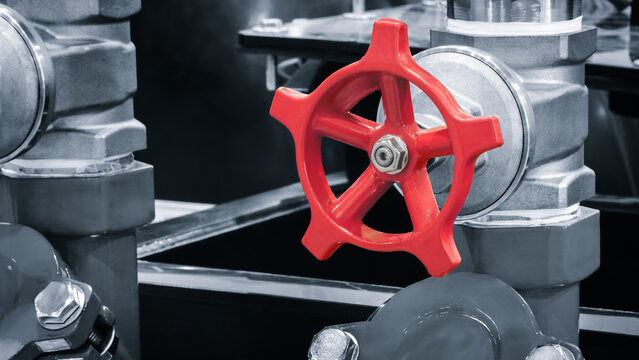 Red valve in an industrial water supply system with koans and pipes