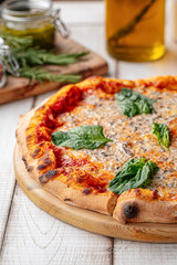 Freshly baked Italian pizza with tomato sauce, spinach leaves, and melted cheese on a wooden board