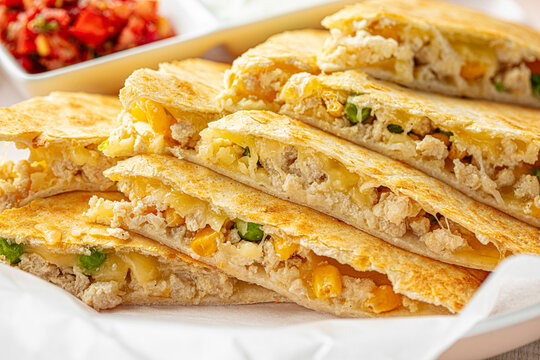Mexican quesadilla with chicken, cheese, and vegetables served with salsa and sour cream
