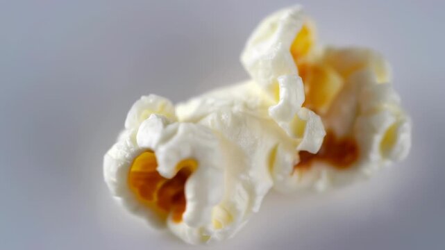 Close up macro shot of a single piece of popcorn on a plain background.