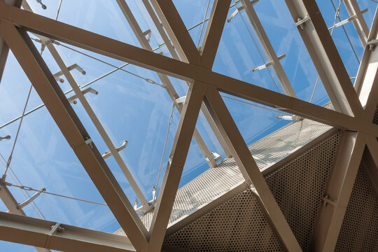 Modern Steel and Glass Architectural Roof Structure With Triangular Geometric Panels and Blue Sky Reflections. Ideal for architectural firms, real estate developers, and modern construction projects.