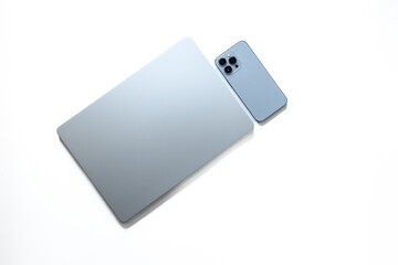 Silver laptop and phone on white background, top view
