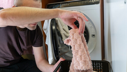 Young man putting clothes in the washing machine