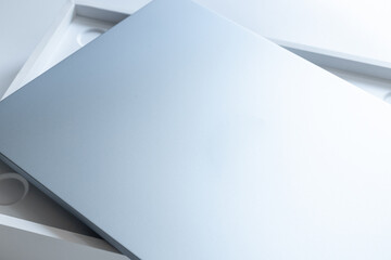 New silver laptop in a box on white background. Unpacking, close up