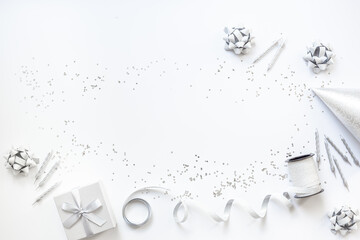 Holiday festive party flat lay with silver carnaval caps and cake candles, top view. Gift box and streamers on white background