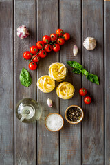 Fettuccine with ingredients for cooking pasta - tomatoes and basil with garlic - on a wooden background, top view. Flat lay