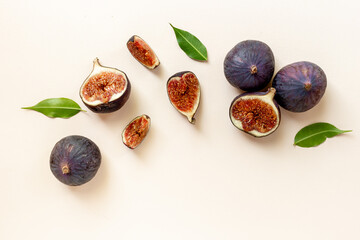 Purple ripe figs fruit and slices with green leaves top view on a stone background