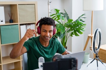 Young man streaming content with laptop and headphones indoors