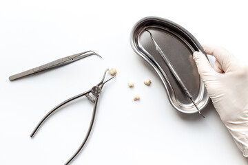 Dentist hand in white medical glove is holding dental equipment tools for teeth care on white background. Professional Dentist desktop, top view