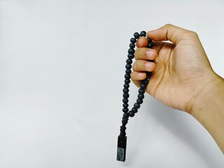 hand holding black prayer beads on white background