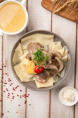 Traditional Kazakh beshbarmak with boiled meat, noodles and rich sorpa broth in a bowl