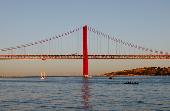 Red suspension bridge and boats in Lisbon, Portugal