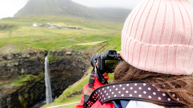 Woman photographing waterfall on Vagar Island