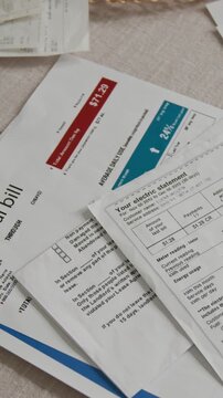 Vertical closeup shot of kitchen table with various household bills and tax documents no people