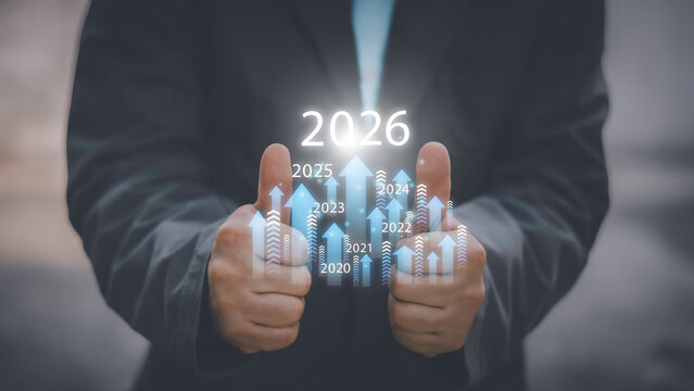 Businessman drawing digital growth arrows and bar graph with 2026 target. Futuristic concept for business goals, technology strategy, data-driven planning, success and innovation.