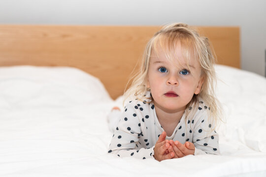 Toddler girl on bed in polka dot pajamas