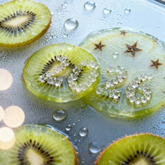 Close up of sliced kiwi fruit with water droplets and decorative sugar crystals on a reflective surface