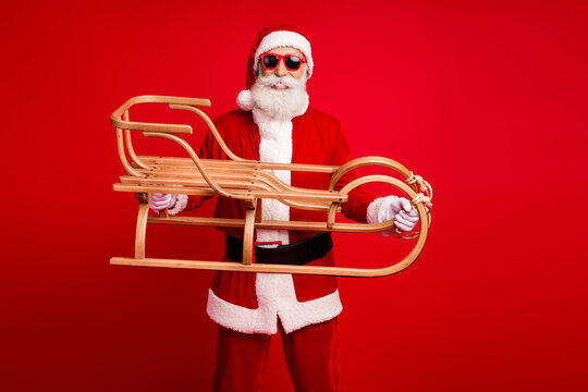 Cheerful Santa Claus holding a traditional wooden sleigh, celebrating the festive holiday spirit against a vibrant red background