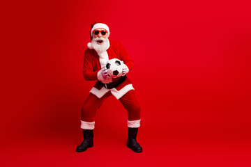 Santa Claus holding a soccer ball on a vibrant red background, showcasing holiday cheer and...
