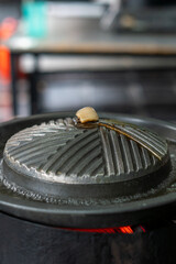 Close-up of Thai-style barbecue grill pan, known as Moo Kratha, with pork belly, shrimp, and vegetables cooking on a hot grill and soup. Popular Asian dining experience in Thailand.
