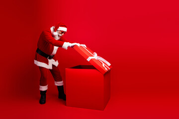 Santa Claus opening a large red gift box in a festive Christmas setting, symbolizing holiday traditions and joy in a cheerful scene.