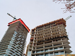 High rise monolith concrete buildings with the cranes above