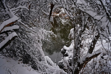 Soldier Lake. The branches of the trees are covered with the first snow. A lake in a mountainous area with a variety of vegetation. November.
