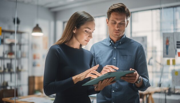 Young Professional Man and Woman Collaborating on Digital Tablet in Modern Office