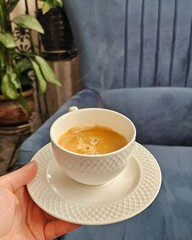  Hot Coffee Cup in Hand with Cozy Interior Background