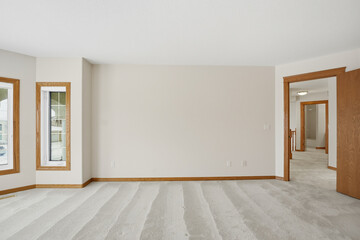 Large empty room with a white wall and wooden trim