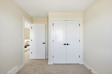 White bedroom with a white door and a white closet