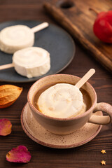 Сhocolate Ice cream in white glaze, cup of coffee, on brown wooden, side view, close up, selective focus
