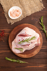 Raw Turkey Thigh with spices on cutting board on brown wooden, linen textile. top view, flat lay, close up