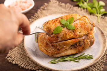 Fried Turkey Thigh with spices on plate on brown wooden with hand, linen textile. side view, close up, selective focus