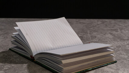 Side view of a hand writing in a notebook, partially framed by an arm in the foreground. Warm shadows and lined pages evoke a quiet, thoughtful writing moment.