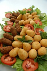 Flat lay of a Brazilian appetizer platter with fried snacks, lettuce, tomato, and lime. Perfect for food blogs, menus, or party planning content.