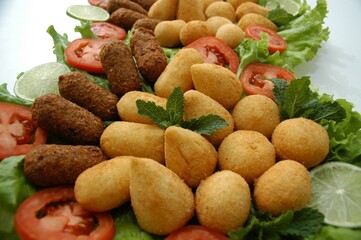 Flat lay of a Brazilian appetizer platter with fried snacks, lettuce, tomato, and lime. Perfect for food blogs, menus, or party planning content.