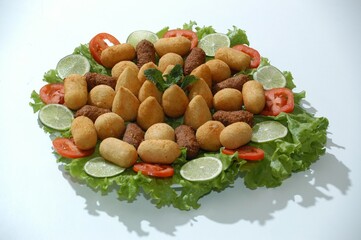 Flat lay of a Brazilian appetizer platter with fried snacks, lettuce, tomato, and lime. Perfect for food blogs, menus, or party planning content.